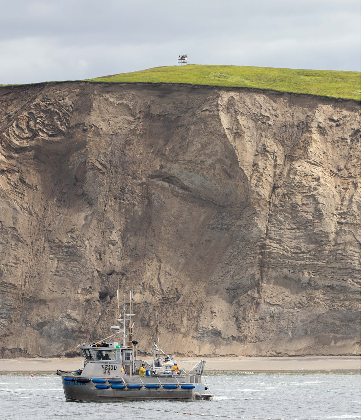 Boat near a large cliff with a grassy top