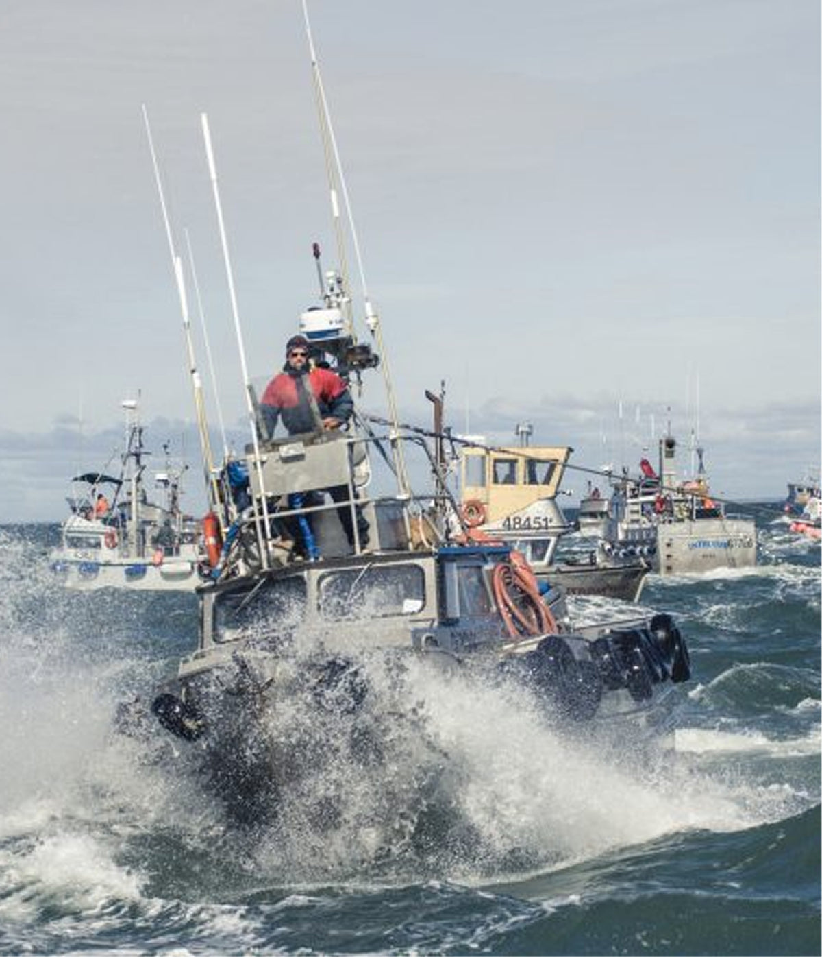 Fishing boat with people on board navigating through choppy waters.