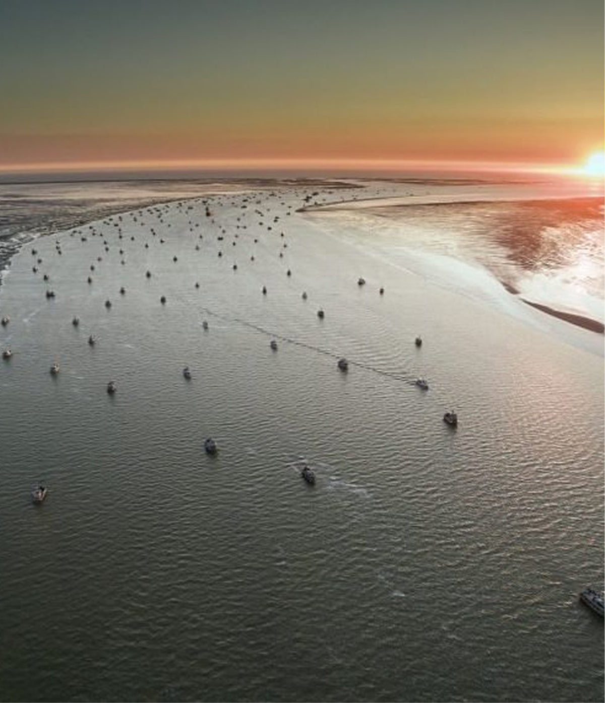 Aerial view of boats on a large body of water at sunset.